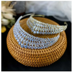 Two silver super flash zircon crown tiaras with intricate diamond-like embellishments displayed on a woven wicker base