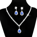 Silver v-shaped crystal bridal jewelry set featuring a sparkling silver necklace with blue teardrop gemstone and matching earrings