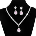 Silver v-shaped crystal bridal jewelry set featuring a sparkling silver necklace with pink teardrop pendant and matching earrings