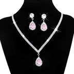 Silver v-shaped crystal bridal jewelry set featuring a sparkling silver necklace with pink teardrop pendant and matching earrings