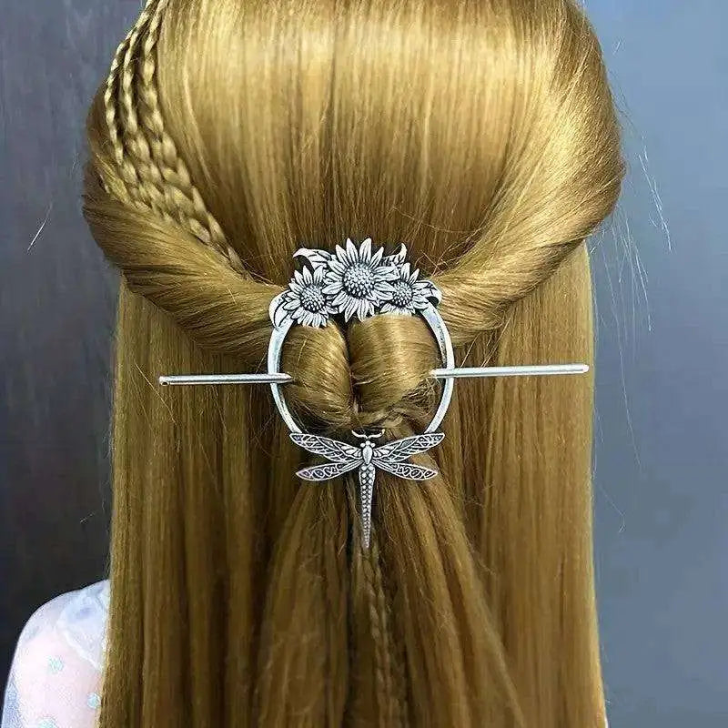 Silver-toned female viking barrette with ornate circular design featuring three sunflowers and a dangling dragonfly in metal