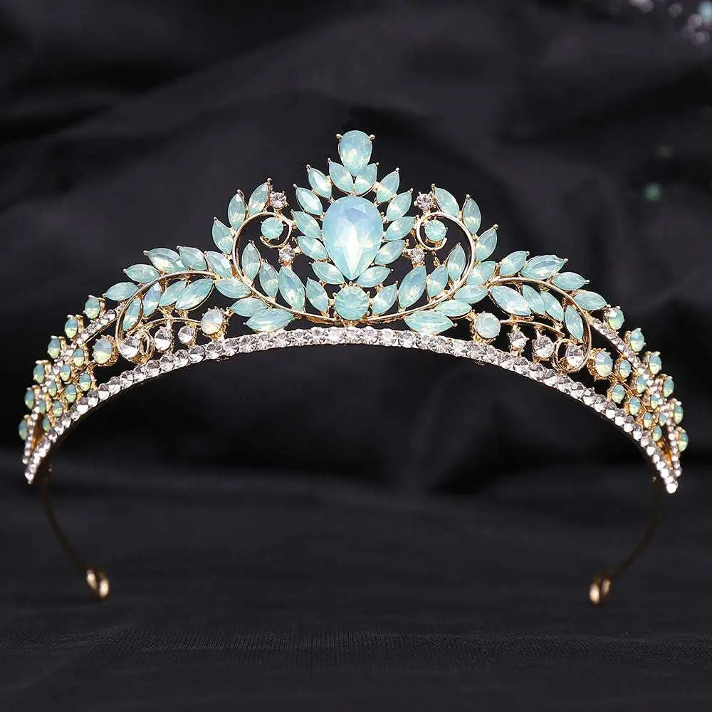 A delicate gold crystal bridal crown featuring light blue teardrop crystals and white leafy opal accents