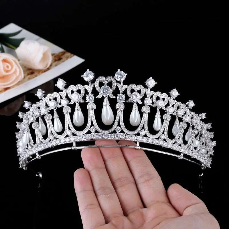 Silver tiara bridal accessory adorned with clear crystals and dangling white pearls for wedding hairstyles