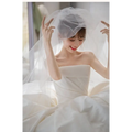 A simple elegant french style satin wedding dress paired with a flowing white satin wedding veil draping gracefully