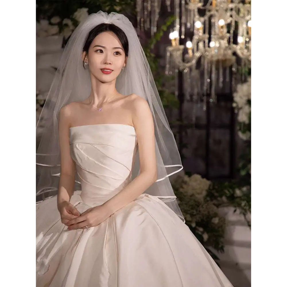 A simple elegant french style white satin wedding dress with a strapless bodice and voluminous skirt