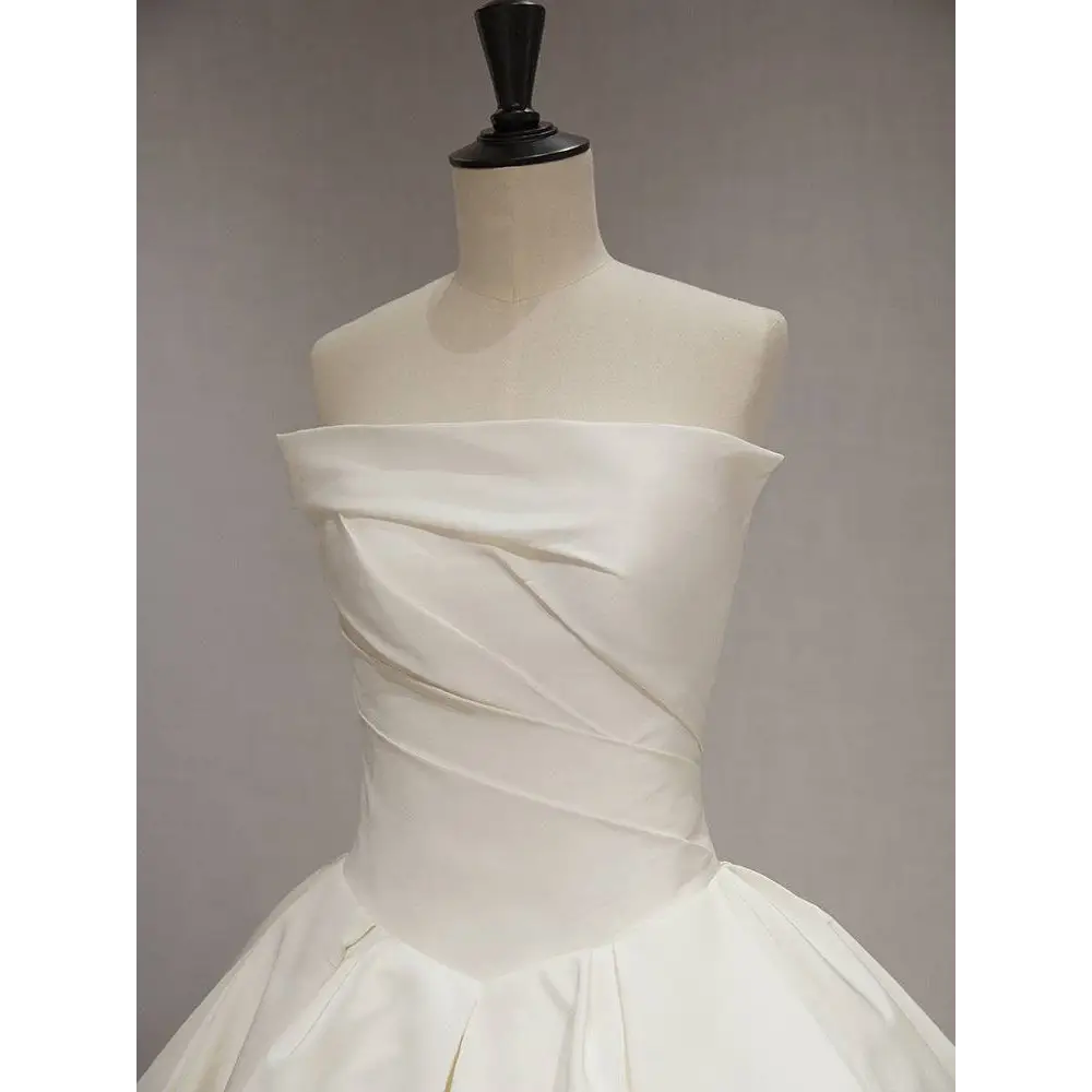 A sleek white satin wedding dress featuring a simple elegant french style with a draped off-the-shoulder bodice