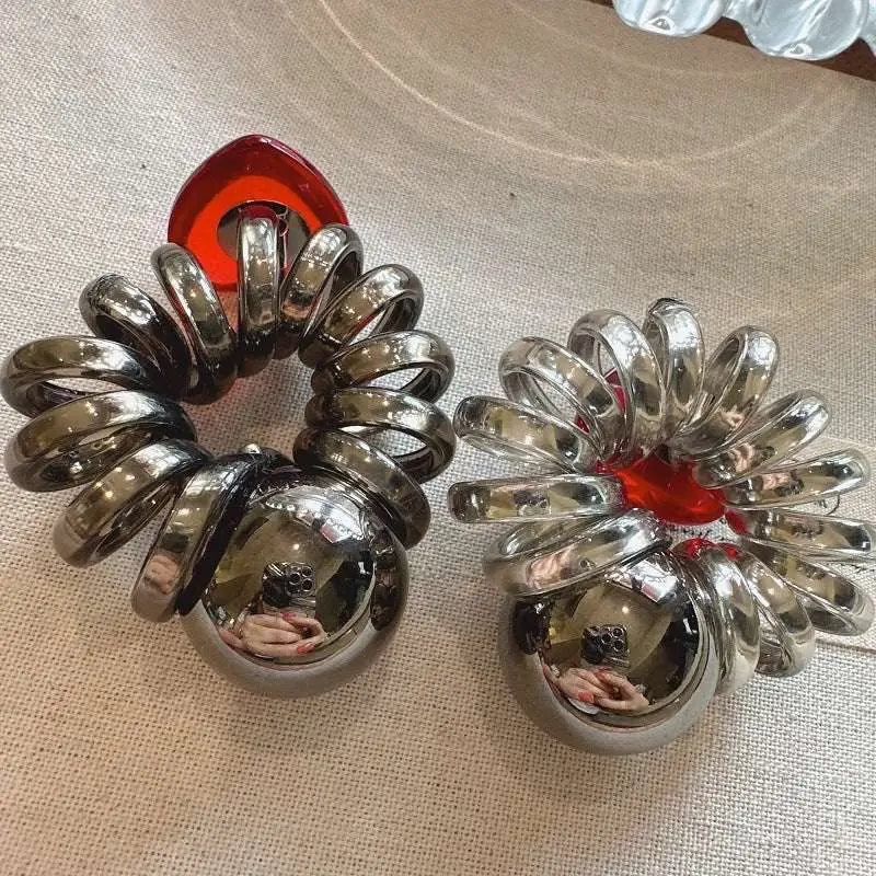 A pair of chrome spiral earrings with reflective spheres and vibrant red resin accents from graceful red love collection