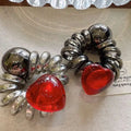 A pair of graceful red love phone line hair rings with shiny coiled chrome springs and vibrant red translucent hearts