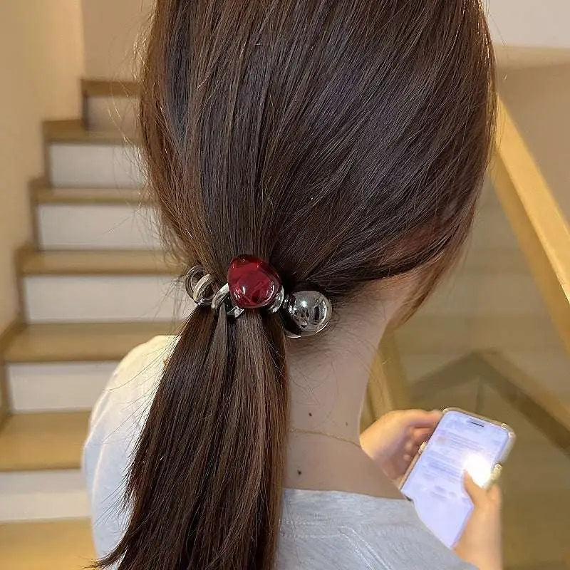A sleek phone line hair ring with a glossy red gemstone and polished silver spheres for graceful red love style