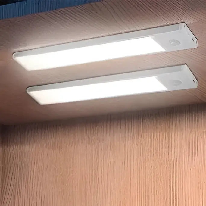 Two sleek white slim motion sensor led cabinet lighting strips mounted under wooden cabinetry for modern use