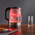 Small glass electric kettle with red led light, black handle, and stainless steel base for quick boiling