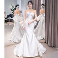 White satin mermaid wedding dress with a large bow at the bodice and small trailing temperament flowing train