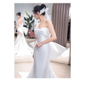 Back view of sleek white satin mermaid wedding dress with dramatic bow and small trailing temperament veil