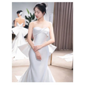 A sleek white satin strapless mermaid wedding dress with a structured bodice and small trailing temperament flares