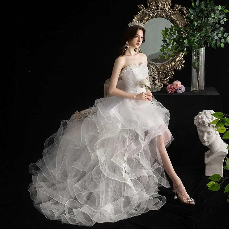 A flowing white small trailing wedding dress with a strapless bodice and layered tulle skirt for elegant occasions