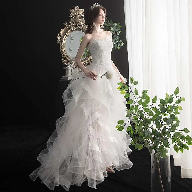 Strapless white small trailing wedding gown with intricate lace bodice and layered tulle skirt elegant design