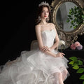 A white small trailing wedding gown with a strapless lace bodice and layered tulle skirt for elegant occasions
