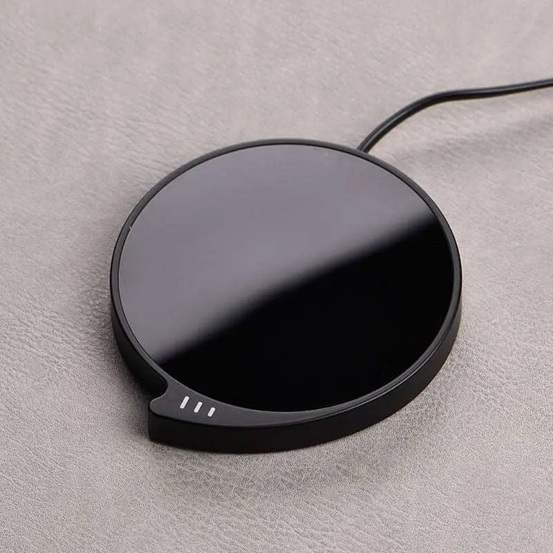 Black circular wireless smart coffee mug warmer with glossy finish and three temperature settings indicator lights
