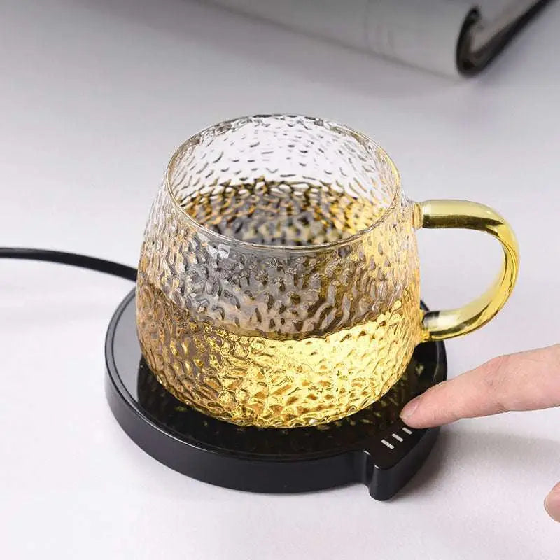 Gold-hammered glass teacup with glossy gold handle on black smart coffee mug warmer with three temperature settings