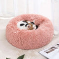 A plush winter warm pet bed in round shape with soft fluffy texture and pink color for cozy comfort
