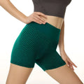 Emerald green high-waisted solid color yoga shorts with textured honeycomb design and matching waistband