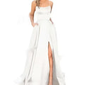 A flowing white satin evening gown with delicate spaghetti straps and a high slit in a solid color design