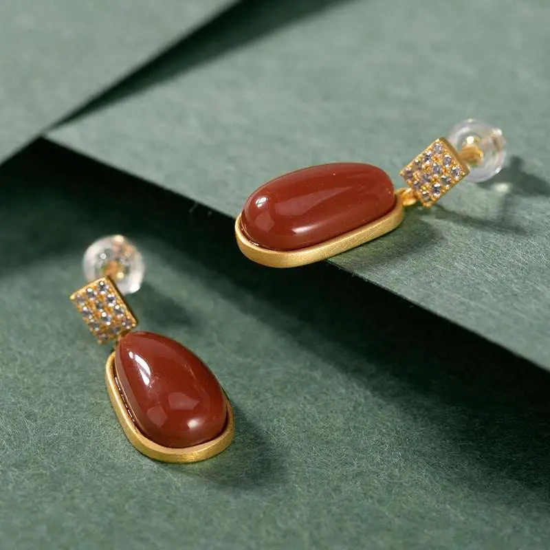 Elegant gold-toned drop earrings featuring southern red agate teardrop stones with square pave diamond accents