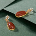 Elegant gold-toned drop earrings with southern red agate oval stones and pave-set crystals in lucky bean earrings design