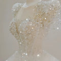 A sparkling beaded white wedding dress with intricate silver beadwork, puffed sleeves, and a voluminous white trailing wedding gown