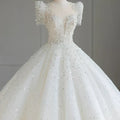 A sparkling beaded white wedding dress with short puffed sleeves and a voluminous skirt featuring intricate beading