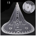 A long flowing white lace wedding dress veil with intricate floral appliqués and a decorative flower embellishment