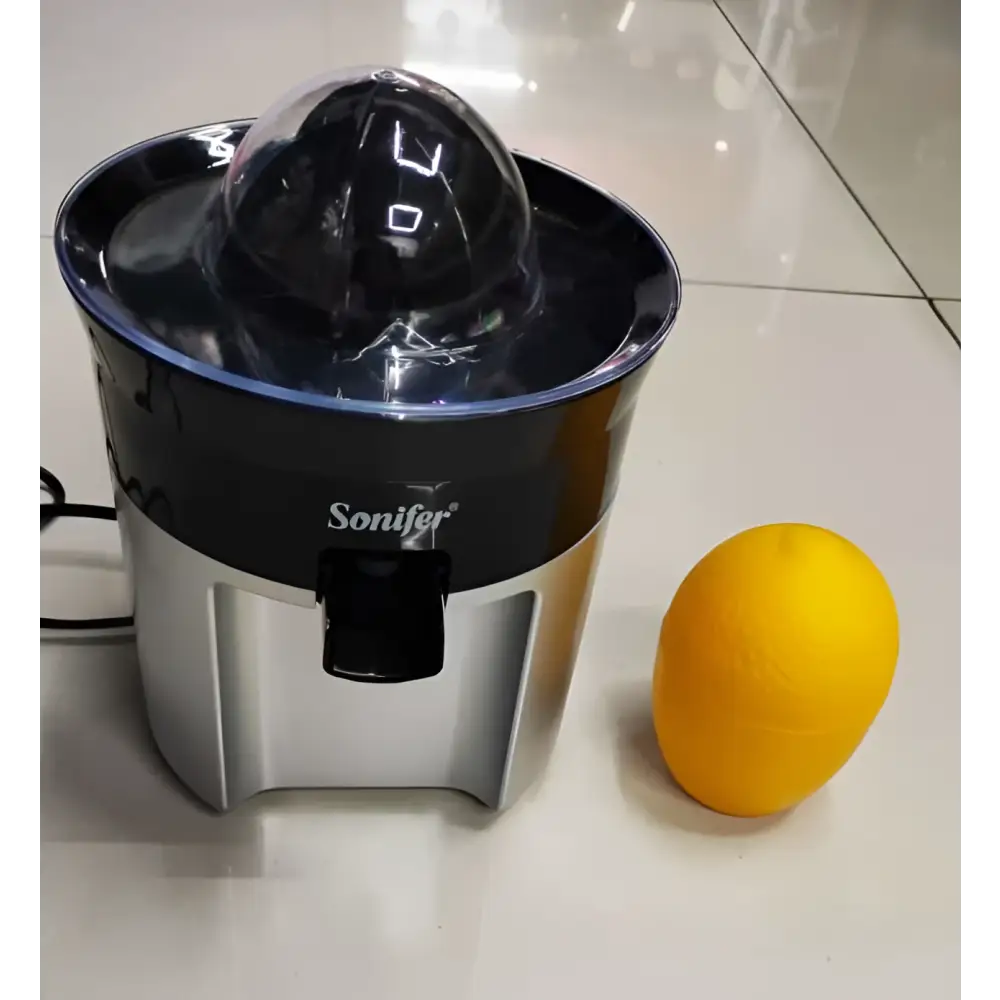 Black and silver steel electric lemon juicer with transparent dome for efficient lemon juicing next to a bright yellow orange