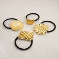 Gold-toned stainless steel flower elastic hair ties with black bands featuring floral and shell-like designs