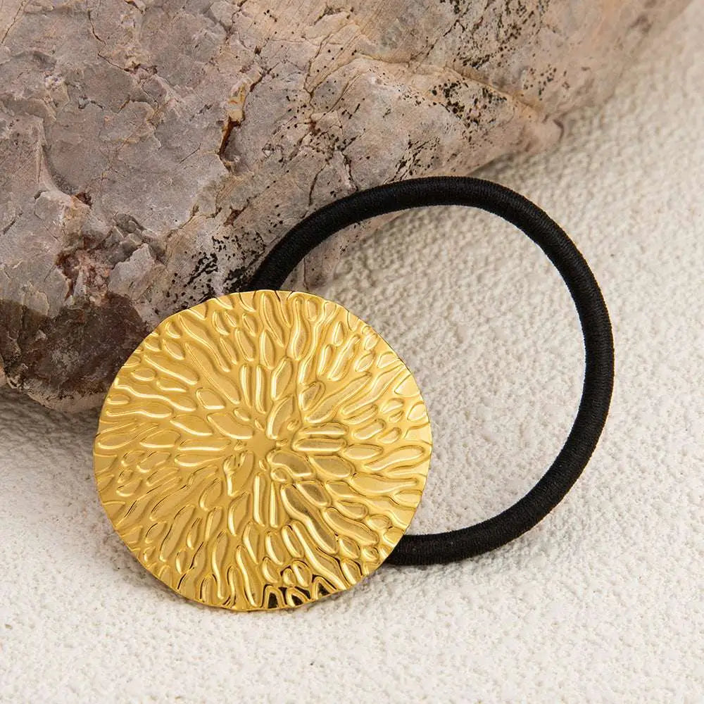 Gold-toned stainless steel flower elastic hair tie with textured leaf pattern and black elastic band for secure hold