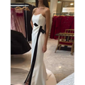 A sleek white strapless black and white contrasting slit dress with a bold black ribbon accent down the side
