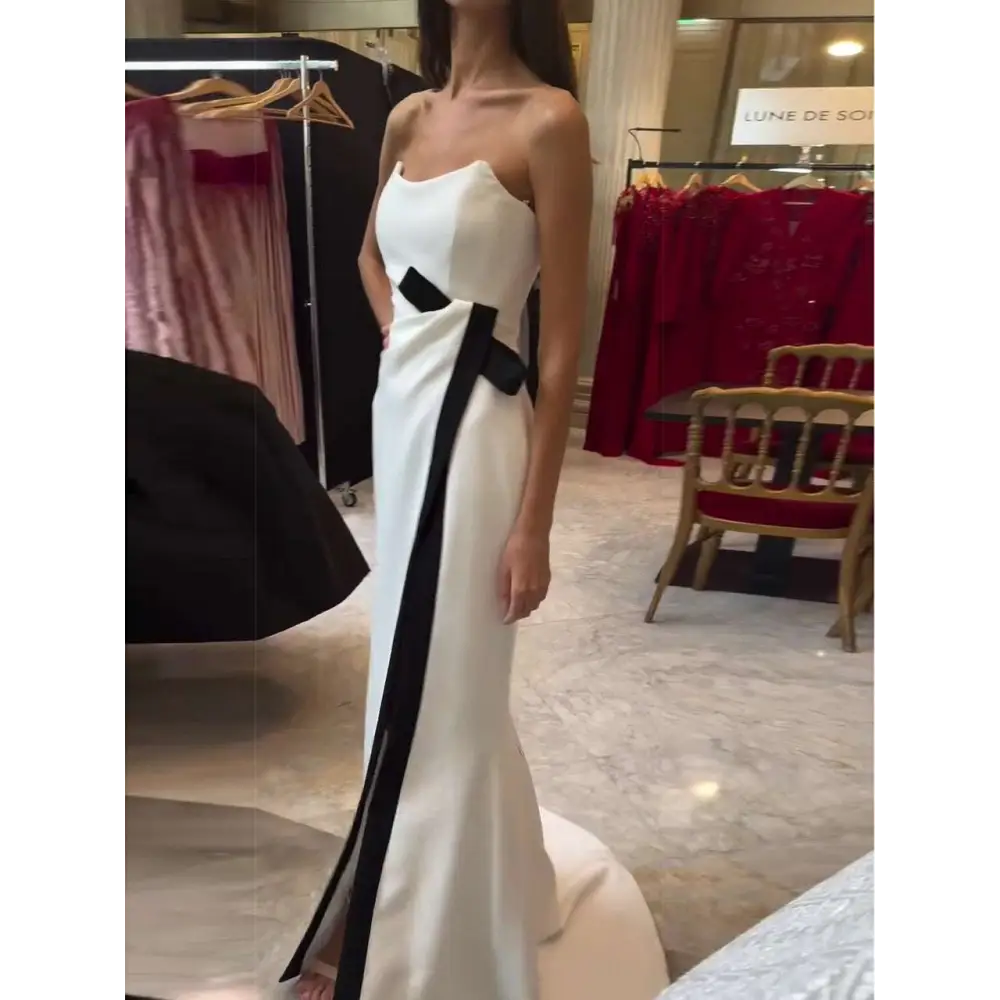 A sleek white strapless black and white contrasting slit dress with a bold black ribbon accent down the side