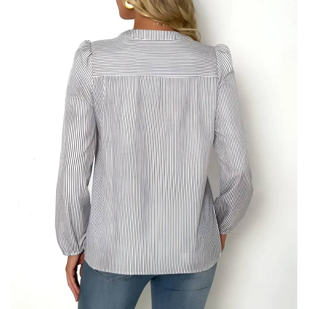A woman wears a long-sleeved striped fashionable versatile shirt with puffed shoulders and a classic collar