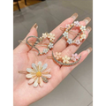 A hand holds pastel pink alloy handmade petal hair clips with delicate floral design and sparkling rhinestone accents
