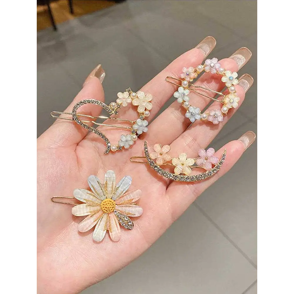 A hand holds pastel pink alloy handmade petal hair clips with delicate floral design and sparkling rhinestone accents