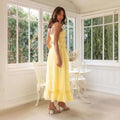 A flowing yellow summer suspender spaghetti strap lace midi dress with fitted bodice and ruffled hem for summer wear