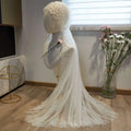 A delicate white sheer bridal hijab adorned with pearls and floral accents in a fairy long pearl veil style
