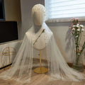 A delicate white sheer bridal hijab adorned with scattered pearls elegantly draped as a super fairy long pearl veil