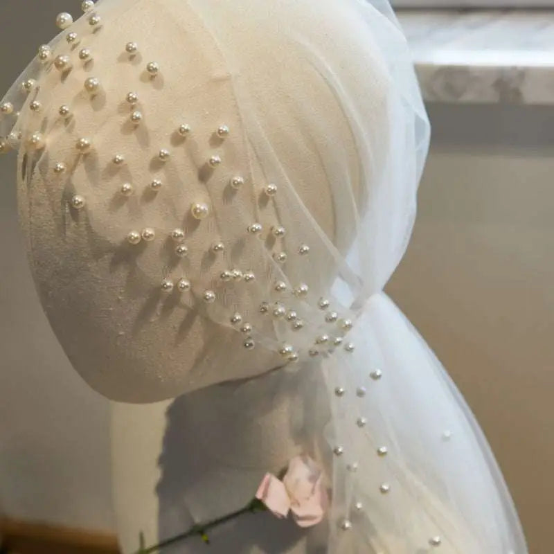 A delicate ivory sheer bridal hijab adorned with scattered silver pearls in a super fairy long pearl veil design