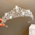 A sparkling silver crown headband with intricate filigree, clear crystals, and a teardrop gemstone from sweet fashion jewelry