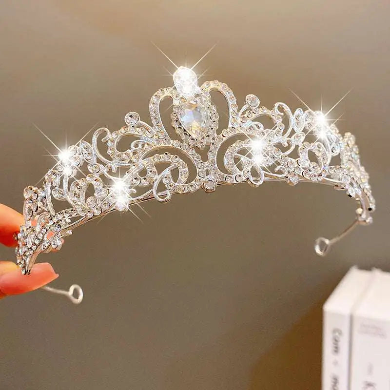 A sparkling silver crown headband with intricate filigree, clear crystals, and a teardrop gemstone from sweet fashion jewelry