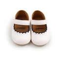 White leather baby princess shoes with scalloped black trim and velcro strap featuring white scalloped trim