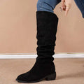 Black suede high leg boot with elastic side panel and low block heel complementing tan slouchy sleeve style