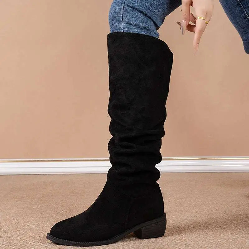 Black suede high leg boot with elastic side panel and low block heel complementing tan slouchy sleeve style