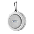 White portable waterproof speaker with perforated grille and carabiner clip for outdoor use in luxury women’s fashion settings