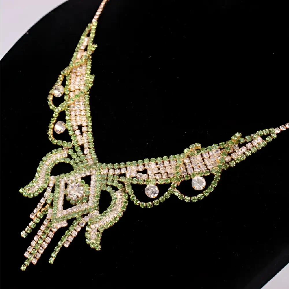 An ornate green and clear rhinestone american exaggerated necklace with flowing designs in a butterfly jewelry set
